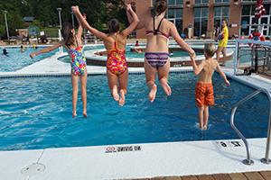 Kids jumping into 矩形 Center outdoor pool.